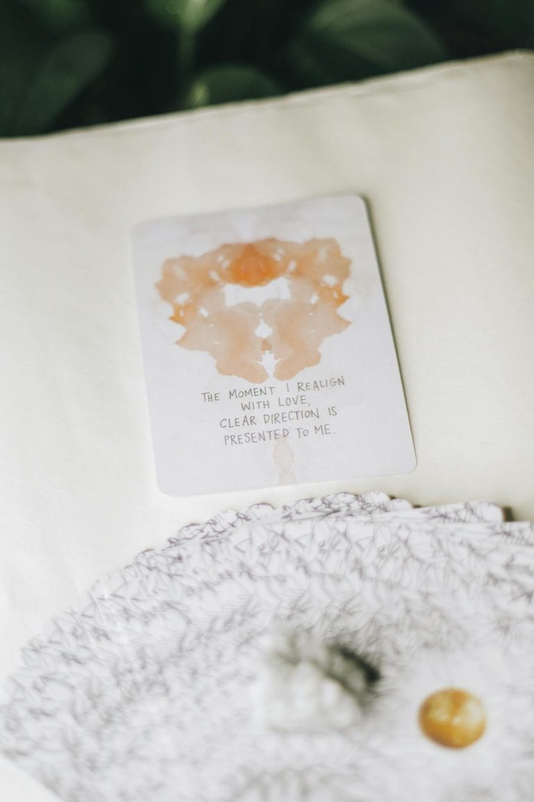 A tarot card with an abstract design and inspirational quote laid on a textured surface.